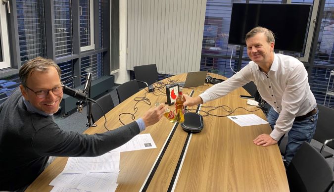 Bild von Dirk Pampel und Dr. Kai Hudetz beim Anstoßen vor dem Podcast